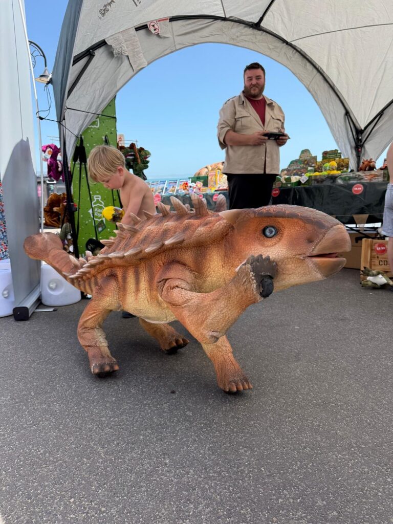 Josh Castree at Lyme Regis Fossil Festival with Spike the Ankylosaur waving at the camera